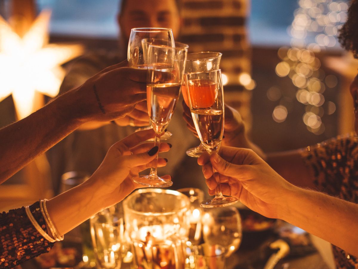 Foto de pessoas blindando com taça de champagne no Ano Novo.