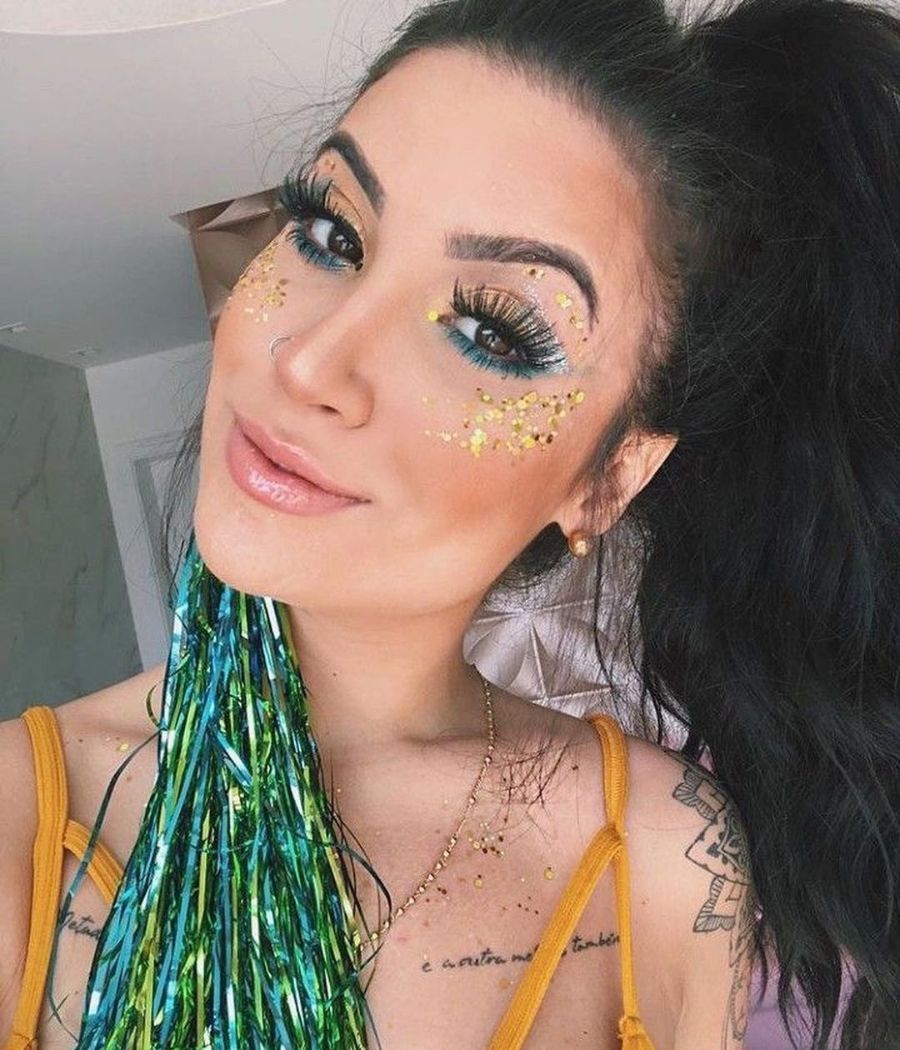 Garota com maquiagem nas cores da bandeira do Brazil e aplicação de pedrinhas no rosto