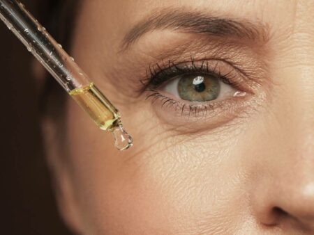 Mulher aplicando sérum nas rugas dos olhos como forma de preenchimento de pele.