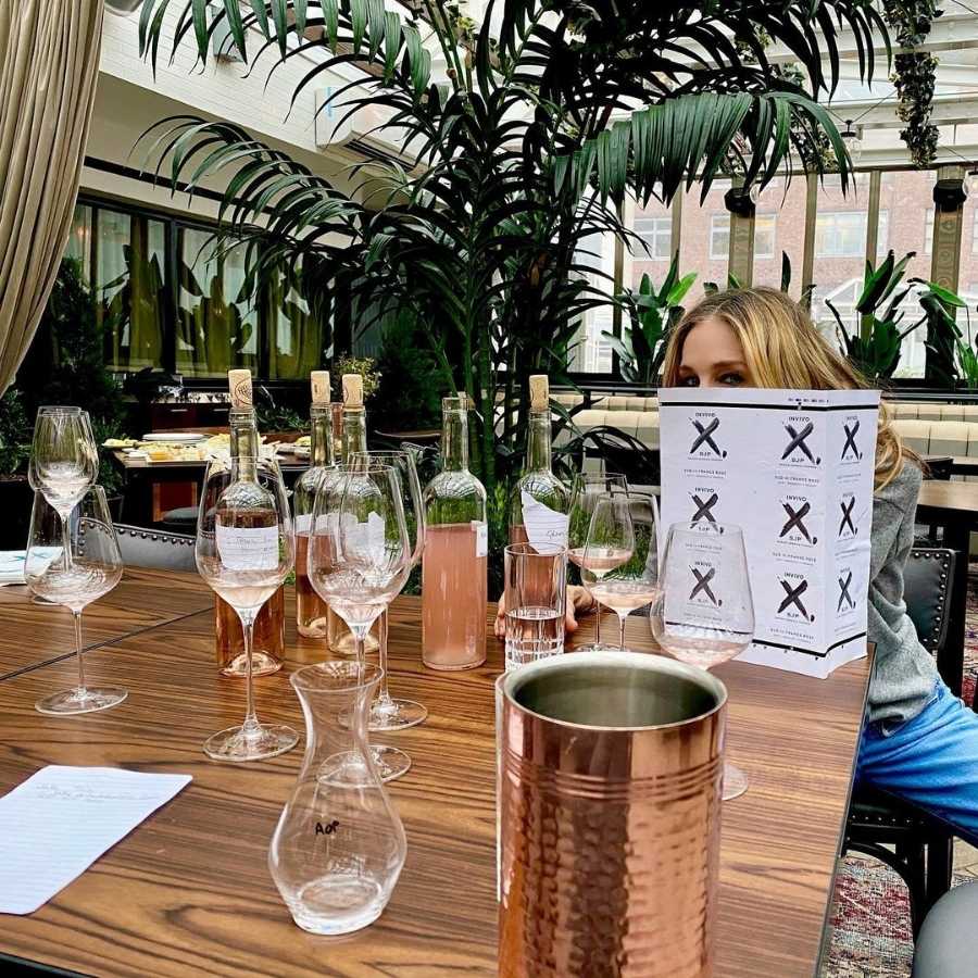 Imagem de Sarah Jessica Parke, atriz, sentada em mesa com diversos vinhos da Invivo & Co.