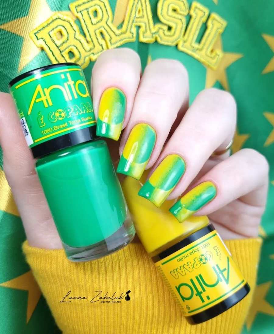 Imagem de mão com unhas decoradas de Brasil.  Cores usadas, verde e amarelo. Fundo da unha verde com amarelo em cima.
