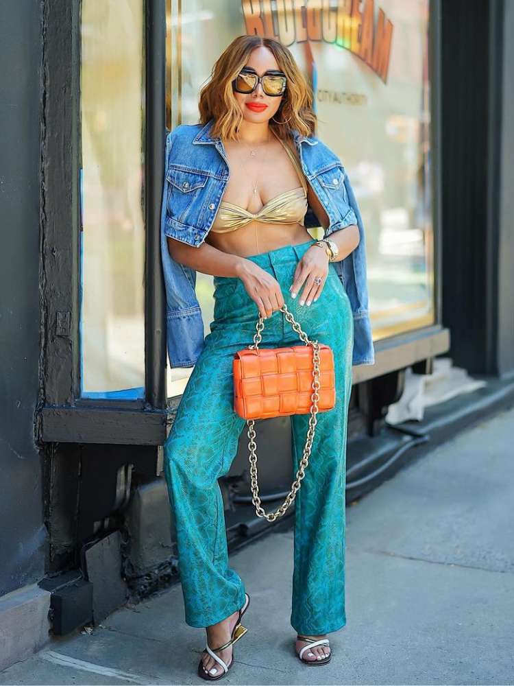 mulher usando look tendência verão 2023: biquíni como blusa, calça de cintura alta e jaqueta jeans