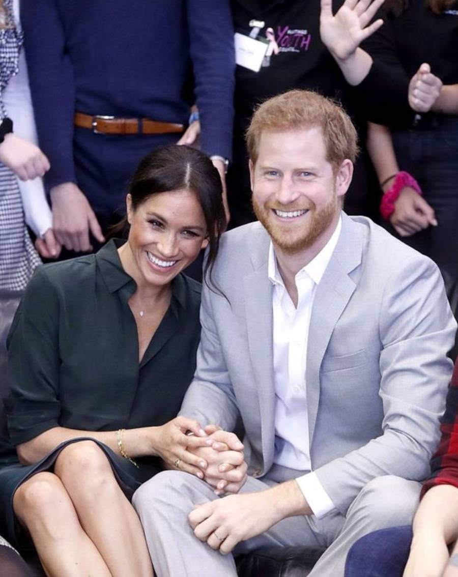 Foto de Harry e Meghan sorrindo durante um evento real