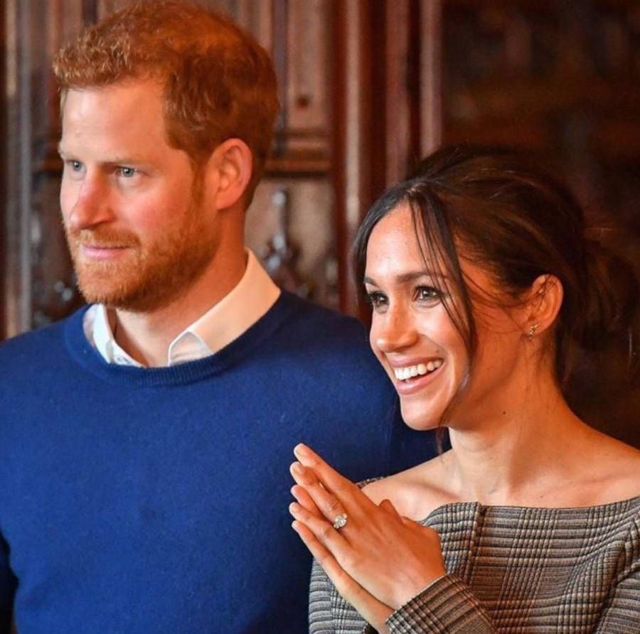 Foto de Harry e Meghan sorrindo para o lado