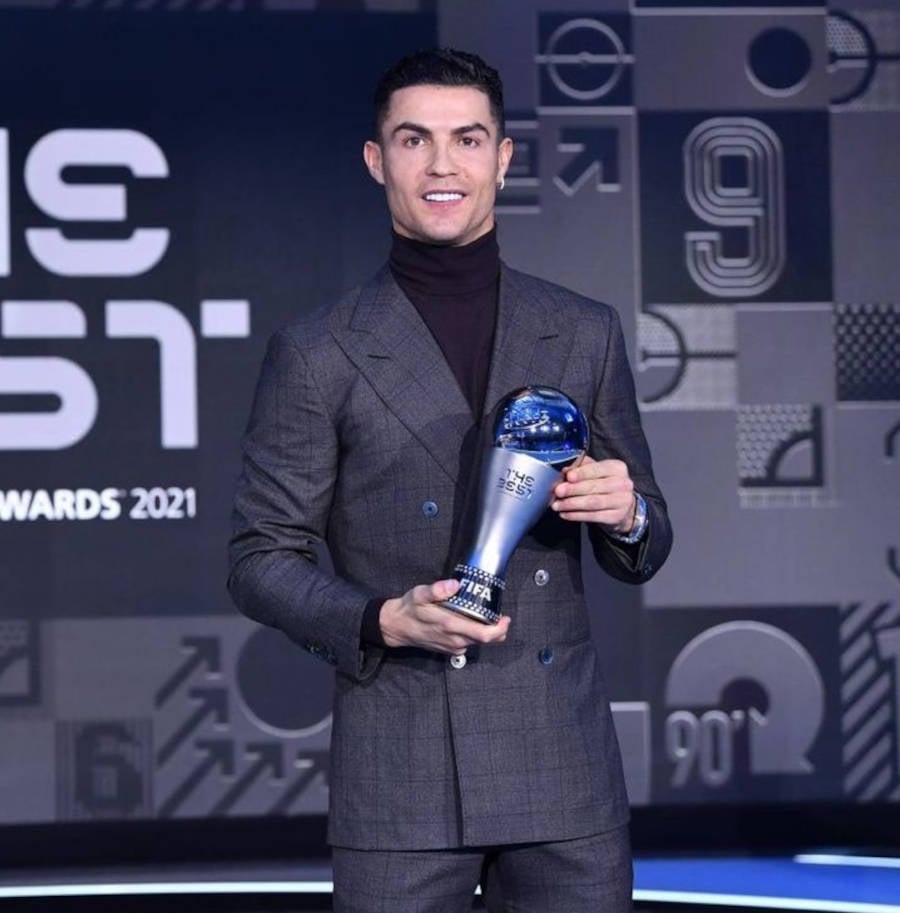 Foto de Cristiano Ronaldo segurando um prêmio vestindo terno