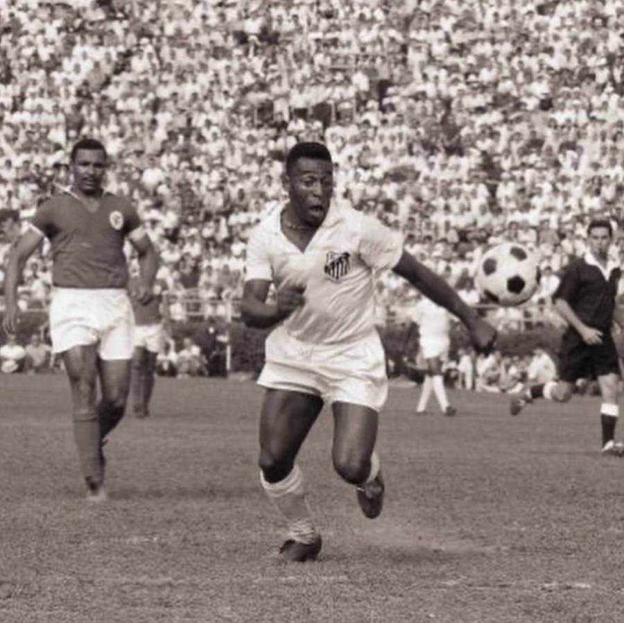 Foto de Pelé enquanto jogava pelo Santos correndo atrás da bola