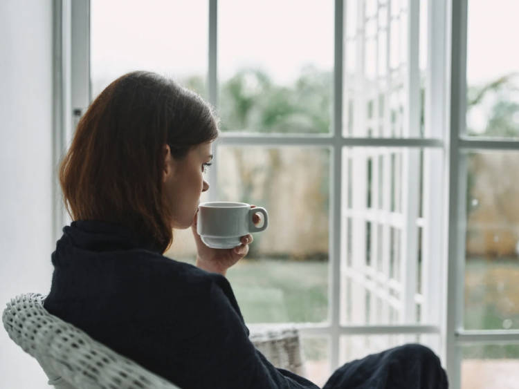 Foto de mulher olhando para o horizonte e bebendo chá
