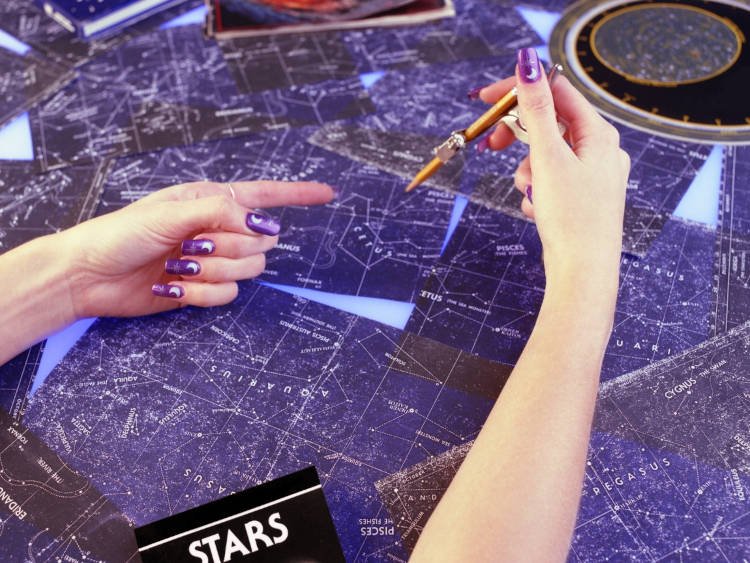 Foto de mulher segurando caneta e vendo os astros