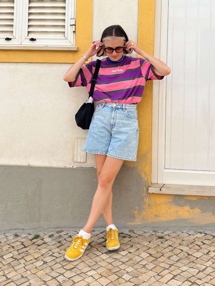 mulher usando camiseta listrada com bermuda jeans, uma das tendências verão 2023