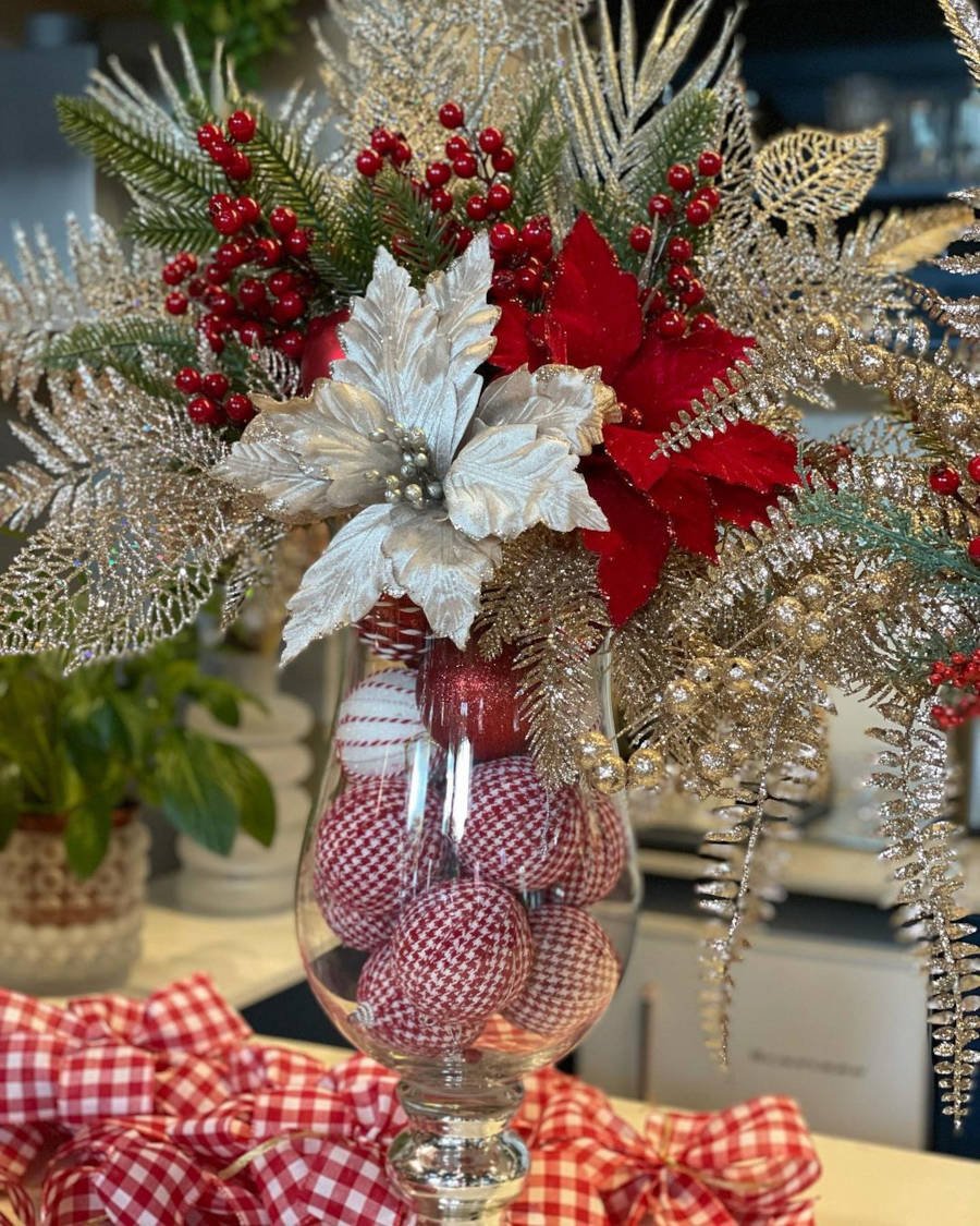 Vaso alto de Natal enfeitado com flores e galhos.