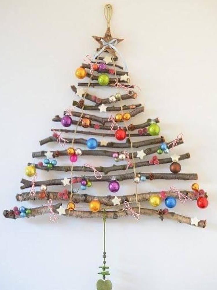 Árvore de Natal feita com galhos na parede e enfeitada com bolinhas coloridas. 