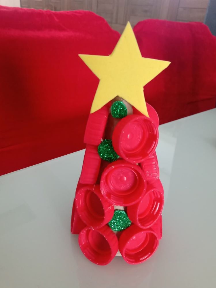 Pequena árvore de Natal feita com tampas e garrafa.