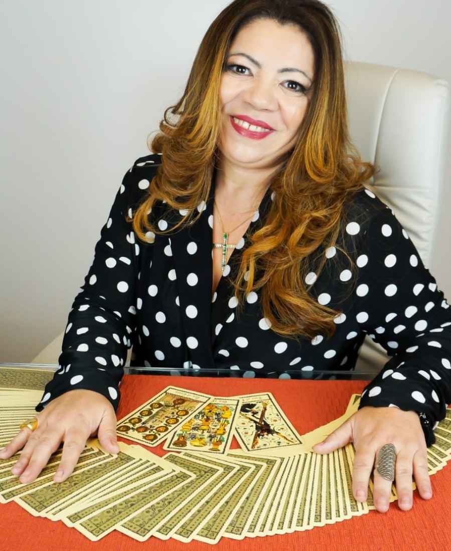 Foto de Taróloga Célia Siqueira sentada em mesa com cartas de tarô espalhadas.