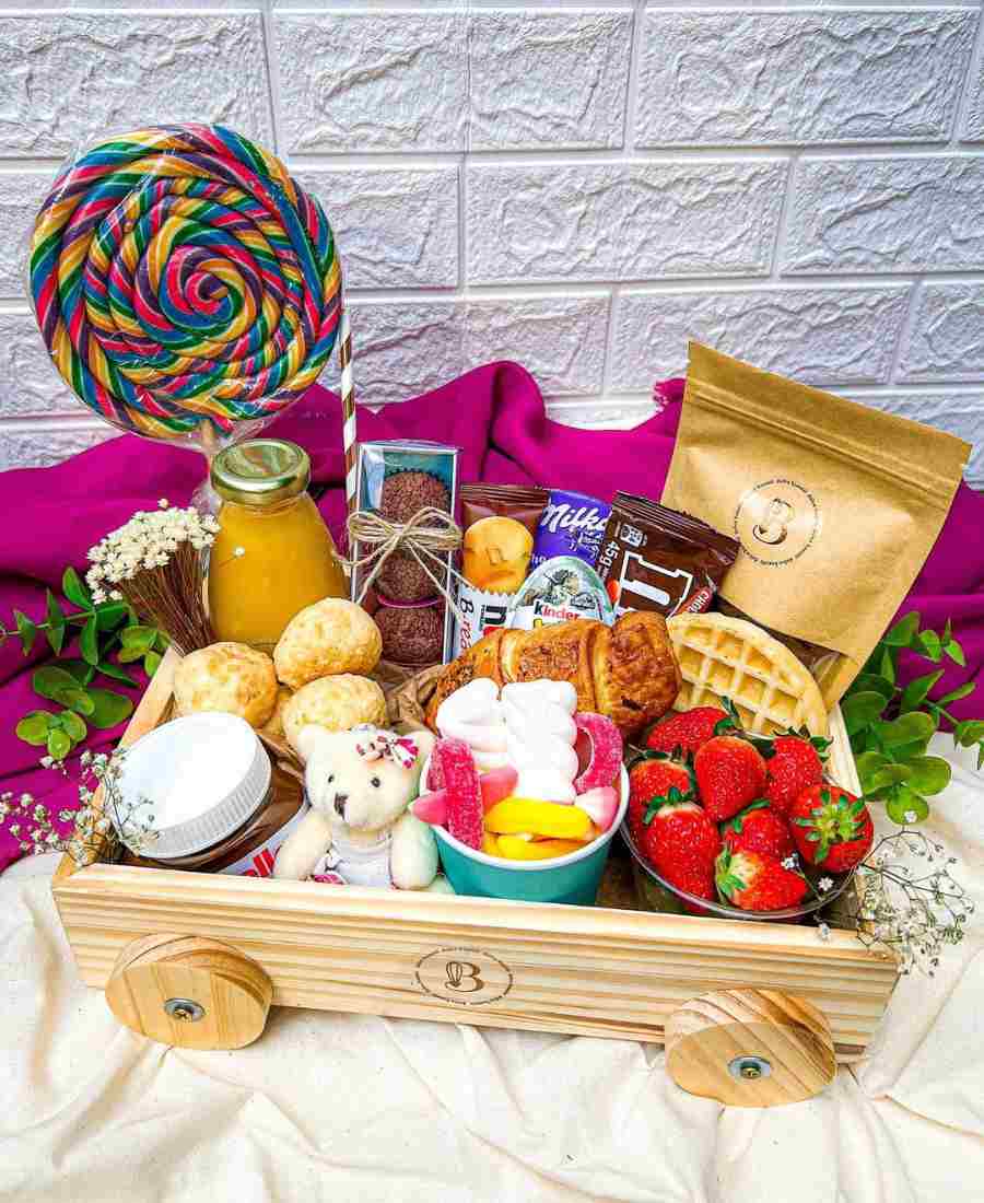 Foto de cesta de doces recheada com: Nutella, balas, pão de queijo, brigadeiro, morango, chocolates, pitulito, etc.