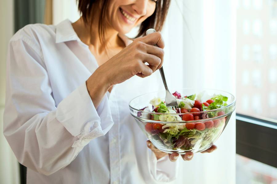 Mulher sem cólica menstrual comendo salada.
