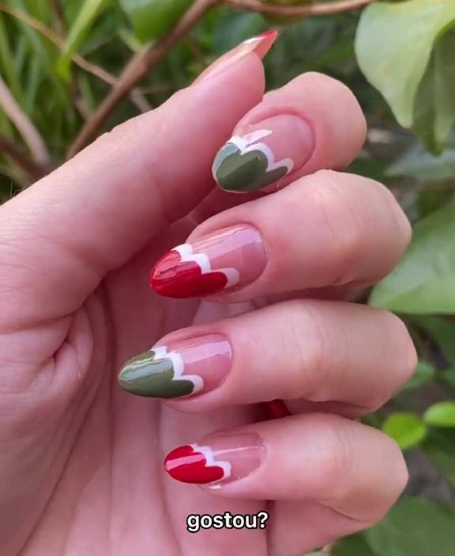 Mão com unha decorada para o Natal em vermelho, verde e branco.