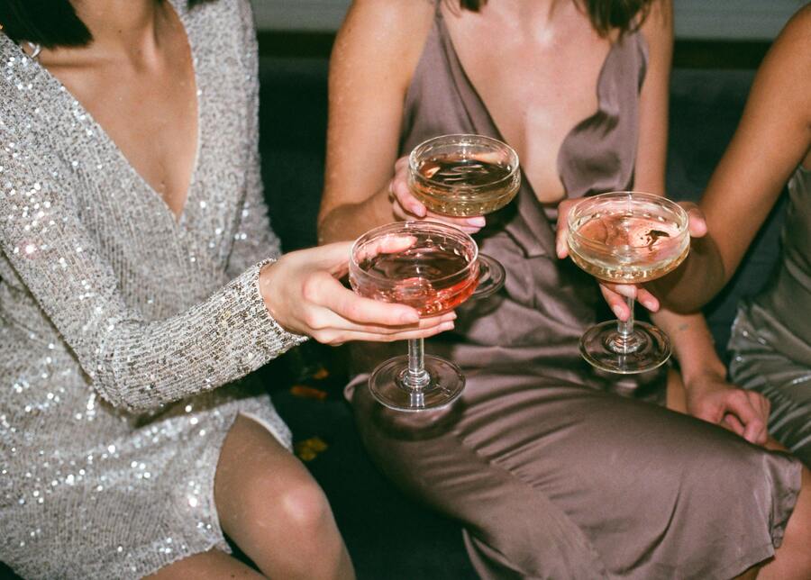 três mulheres esperando para prosperar em 2023 com vestidos de festa e brindando com champanhe