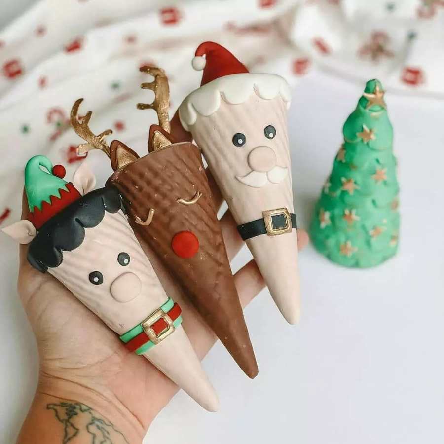 Mão segurando cones doces decorados de Natal.