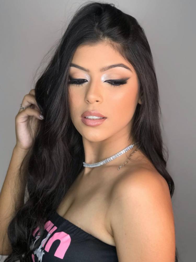 Mulher de pele clara e cabelo preto usando maquiagem, nude com o canto do olho iluminado, delineado gatinho esfumado e batom nude.
