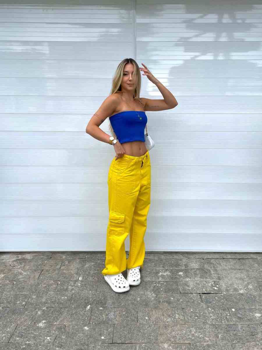Foto de mulher usando cropped azul + calça amarela e crocs.