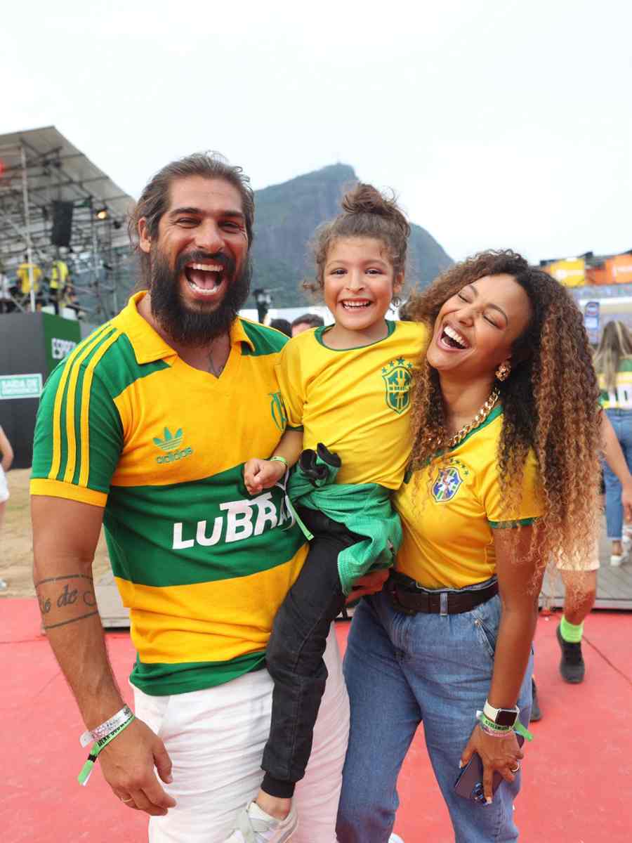 Foto de Saulo Bernard e o filho Benjamin no Festival Village Betano. Eles vestem camisa do Brasil verde e amarela.