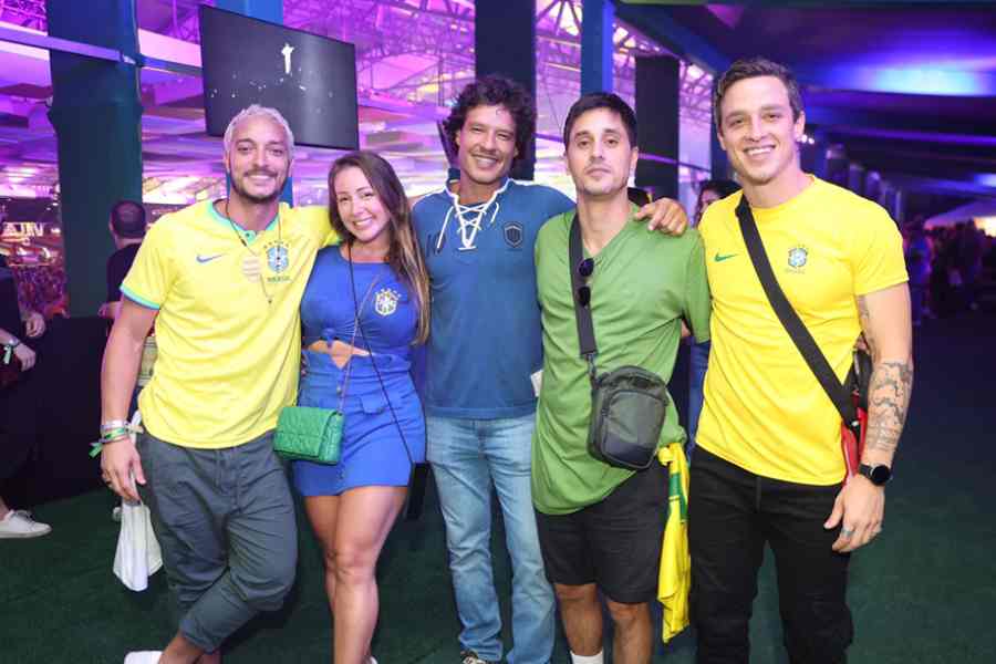 Foto de Allan Souza Lima, Pamela Cancela, Nando Rodigues e Ivan Neves no Festival Village Betano. Todos vestem roupas de cor da bandeira do Brasil para a Copa do Mundo.