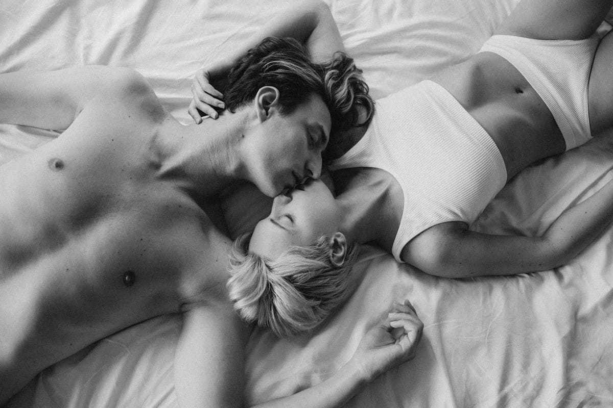 casal deitado na cama, se beijando