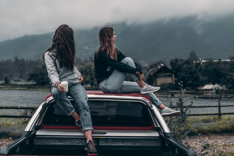 Duas meninas sentadas em cima de um carro olhando a estrada