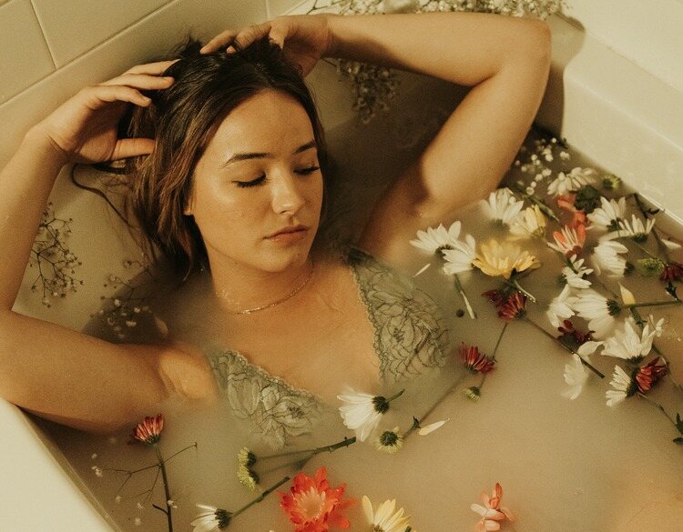 Mulher de roupa íntima tomando banho de banheira com flores