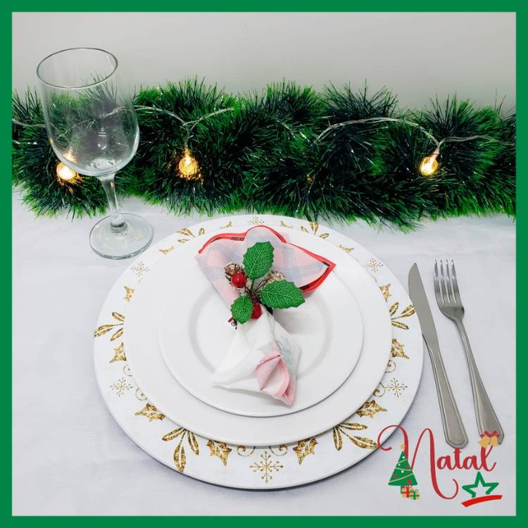 Mesa posta com taça, sousplat natalino branco e dourado e pratos brancos. 