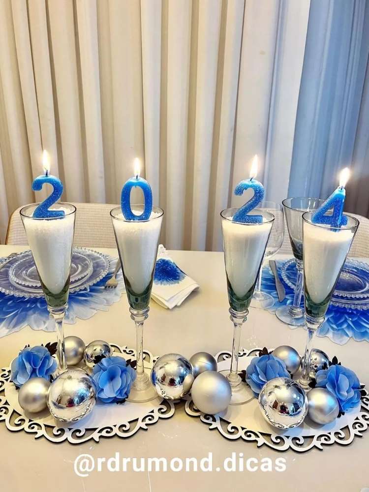Velas azuis de 2024 em taças na mesa posta em tons de prata e azul.
