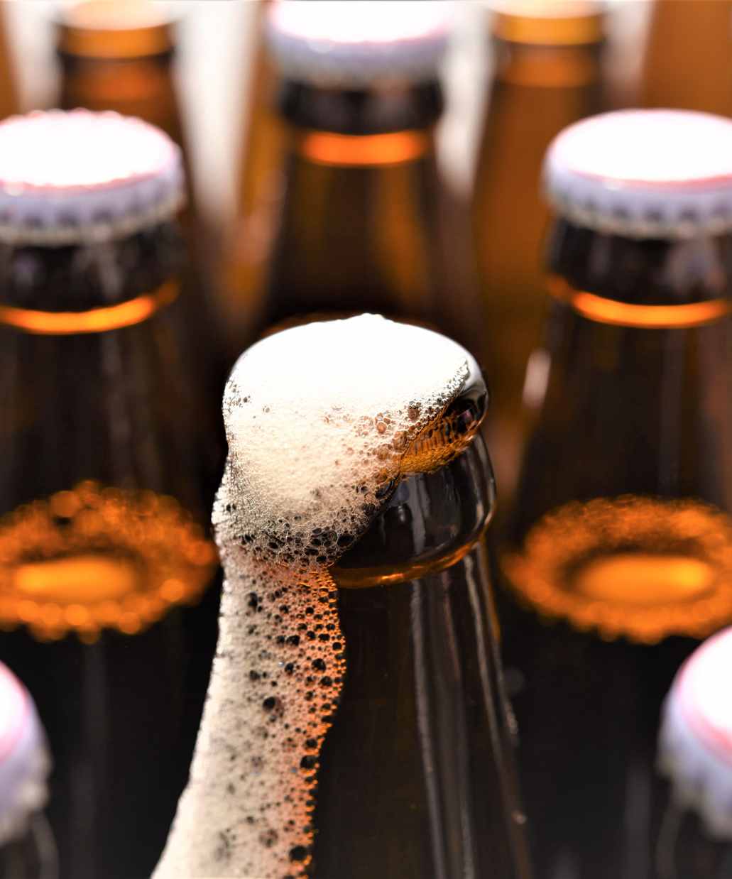 Foto de garrafas de cerveja, uma com a tampa aberta.
