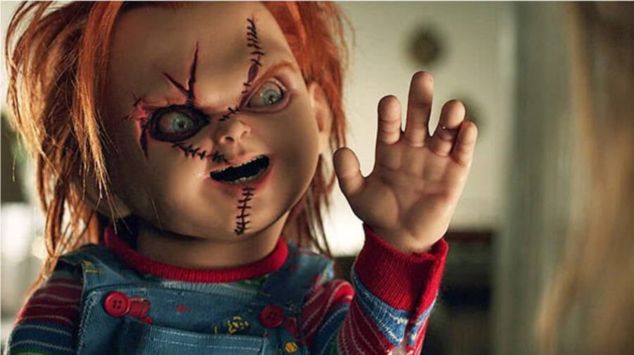 o boneco assassino Chucky com a mão estendida e cicatrizes no rosto