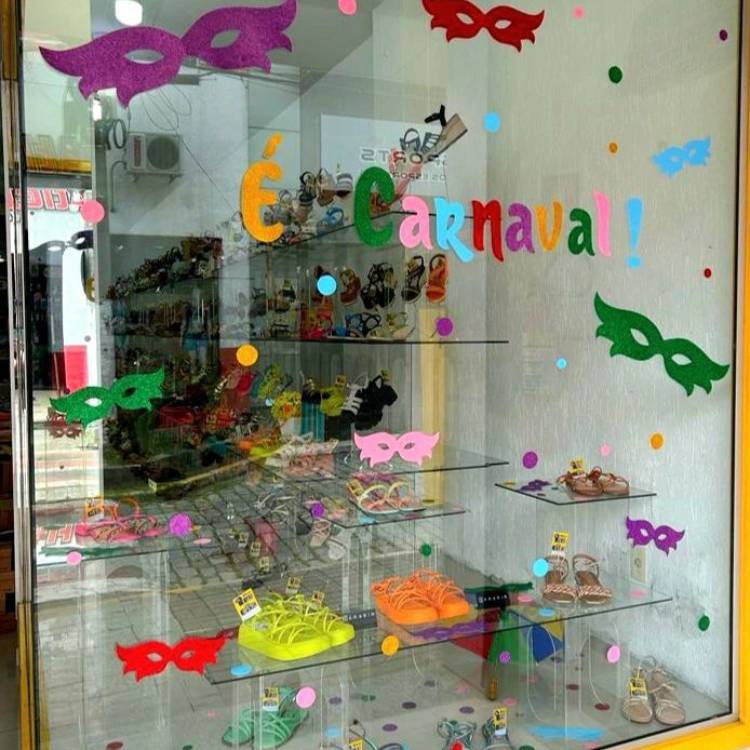 Vitrine de loja de calçados com máscaras coloridas coladas no vidro e a frase "É Carnaval". 
