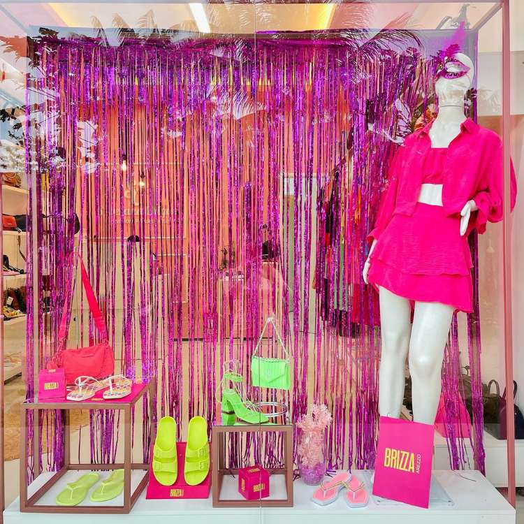 Vitrine de loja de roupas e calçados femininos com máscara, brilho, serpentina, tudo em rosa