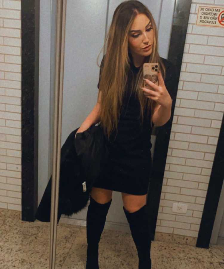 Sister do Big Brother Brasil 2023 com look preto de festa em selfie de frente a espelho de elevador.