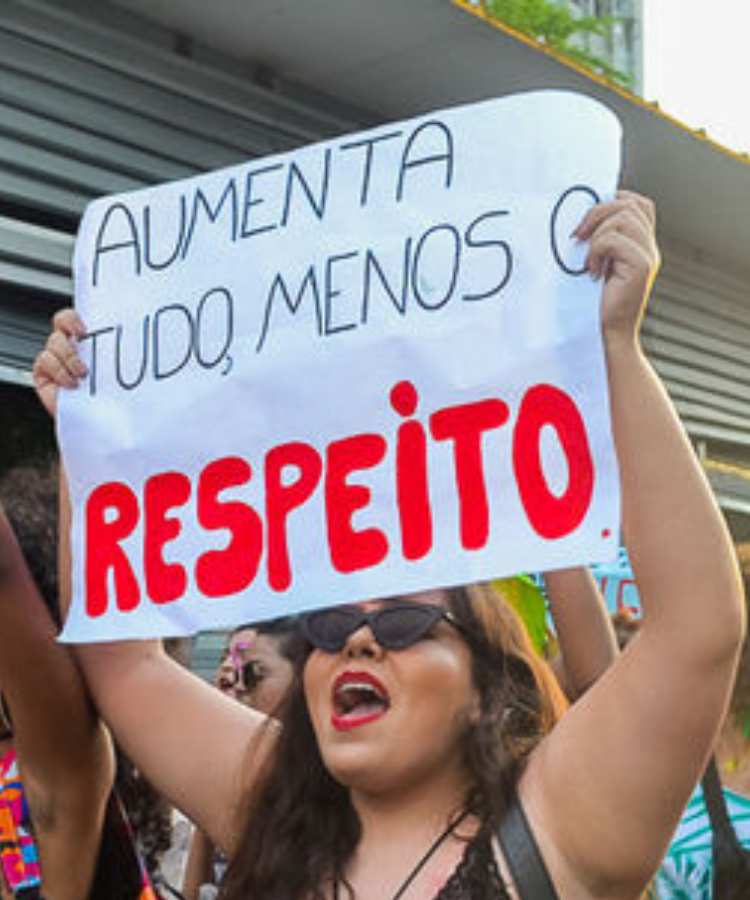 Mulher com cartaz em manifestação feminista com a frase: aumenta tudo, menos o respeito.