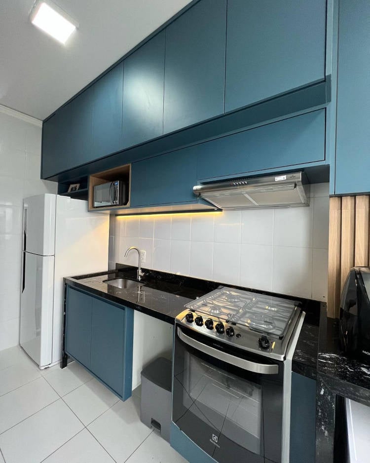 Cozinha azul com fogão e geladeira.