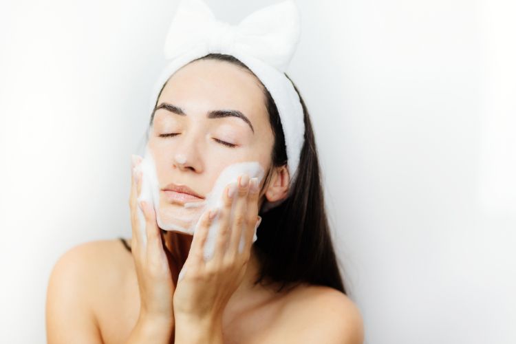 Mulher limpando o rosto na rotina de cuidados com a pele depois da ressaca