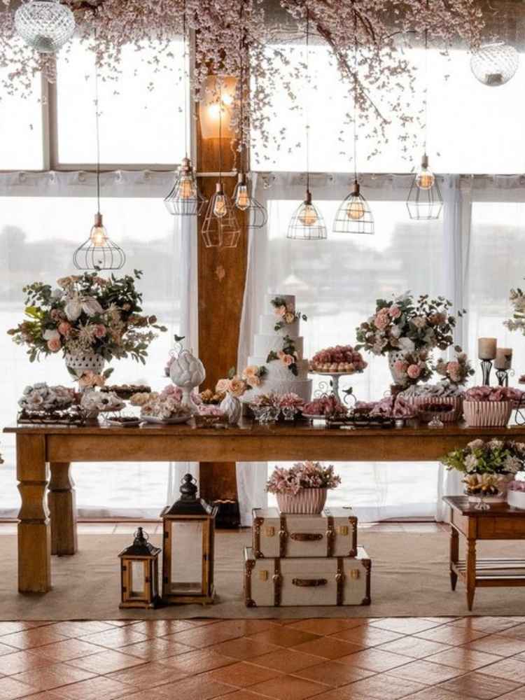 Decoração de mesa de casamento rústica com malas e lanternas.
