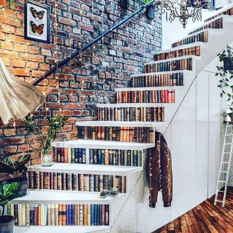 Escada com livros e corrimão na parede.