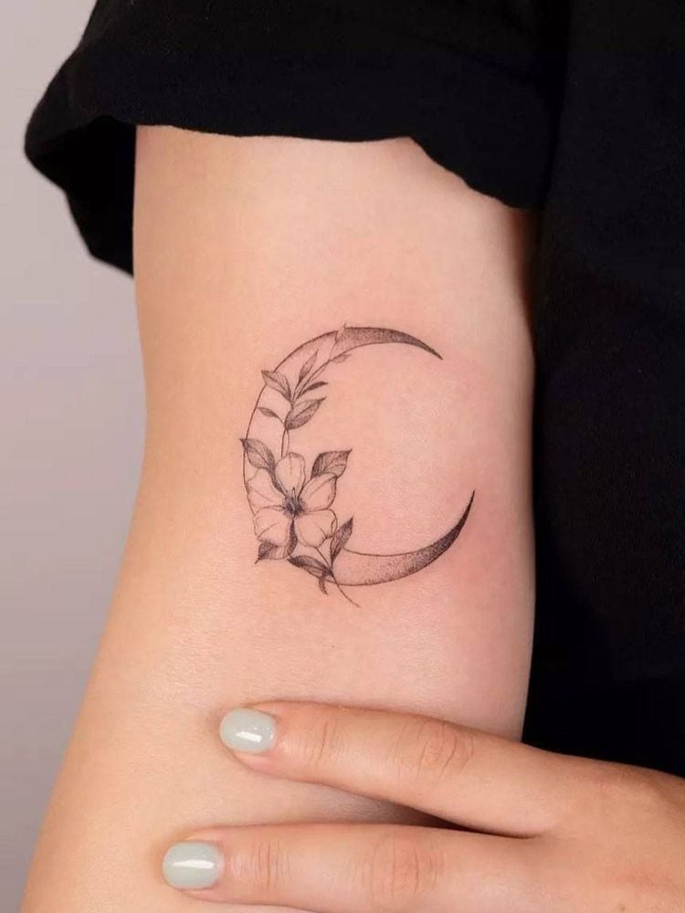 Foto de tatuagem da lua, com um ramo de flor. 
