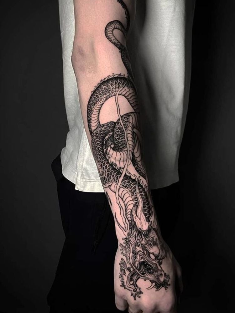 Foto de tatuagem de dragão por todo o braço. 