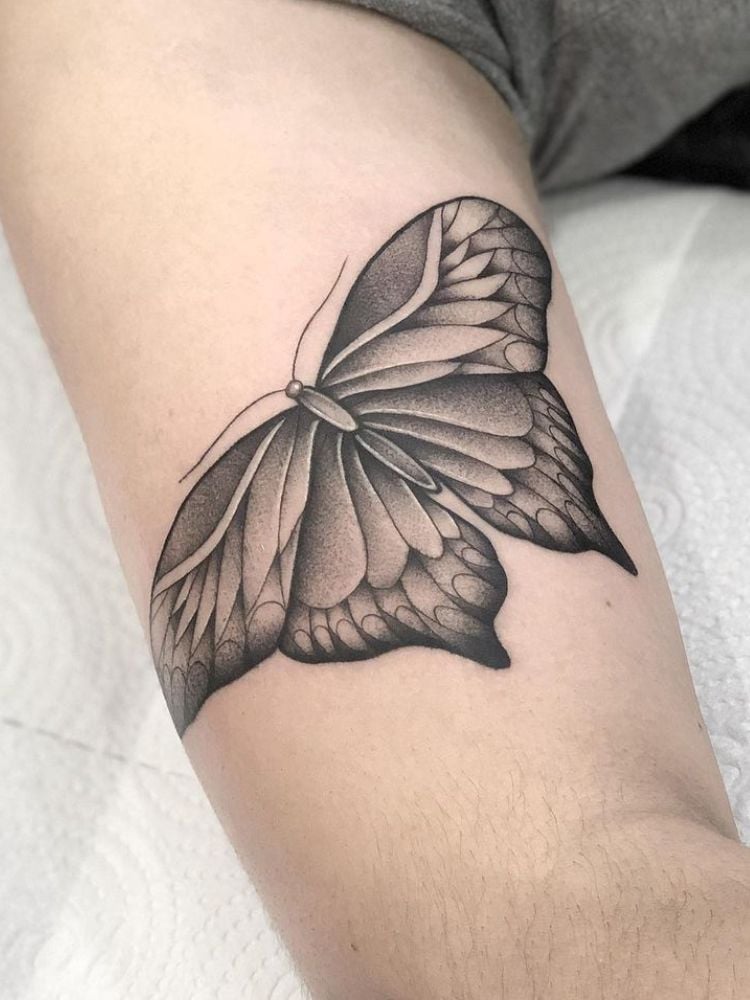 Foto de tatuagem de borboleta no bíceps.