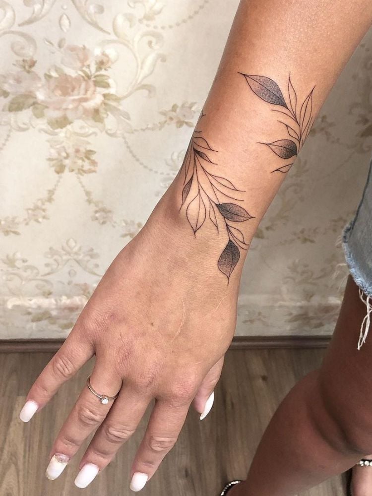 Tatuagem de ramo de folhas do antebraço ao pulso.
