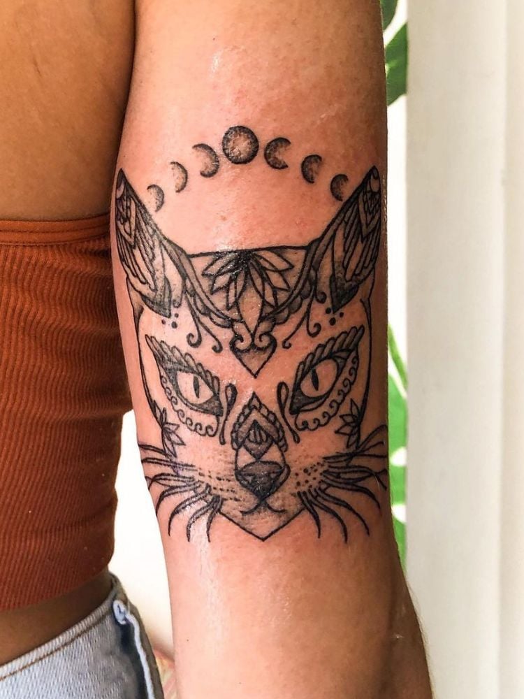 tatuagem de gato com fases da lua, no tríceps. 