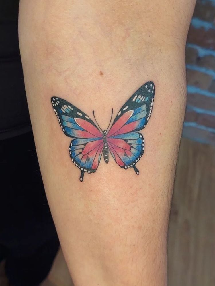 Foto de tatuagem colorida de borboleta no antebraço.