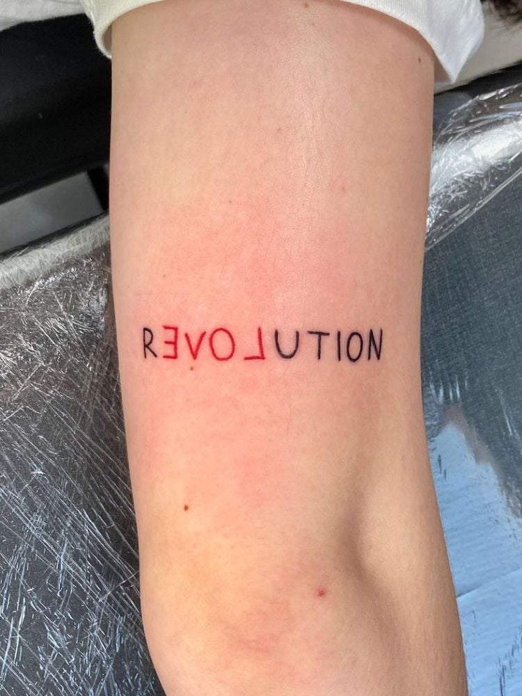 tatuagem com a palavra "revolution".
