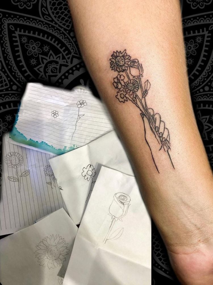 Foto de braço com tatuagem de várias flores.