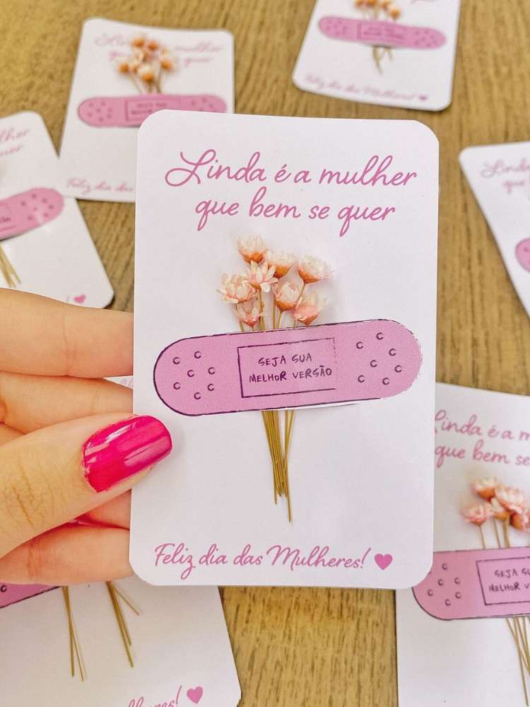 Cartão com mensagem "Linda é a mulher que bem se quer", banda-aid rosa e flor sempre viva